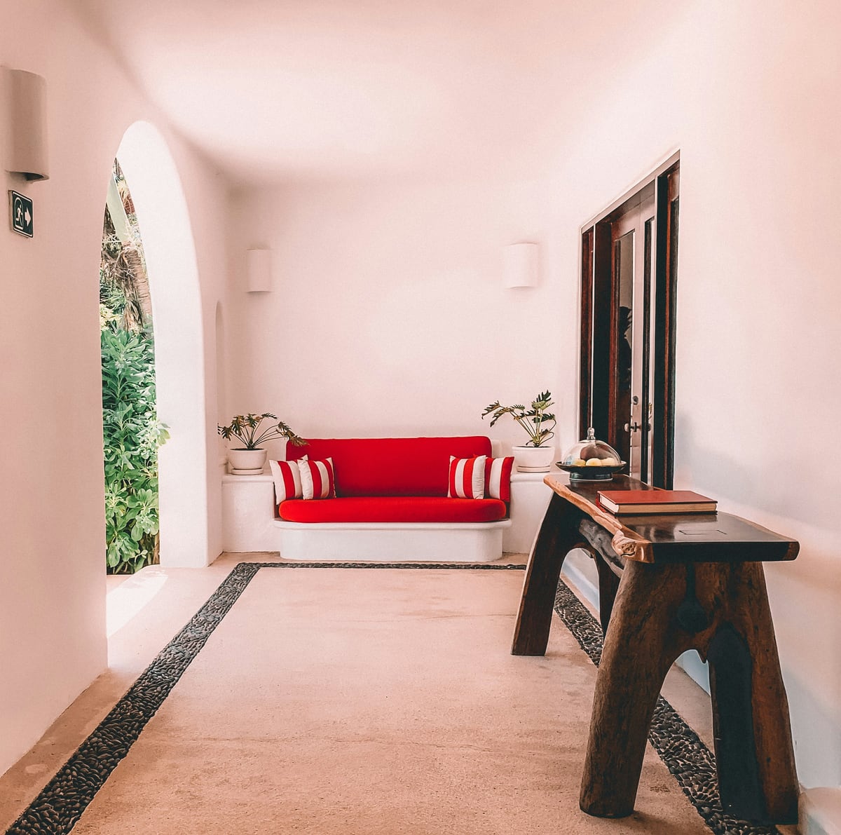 A sculptural white lounge with a red sofa and garden archway