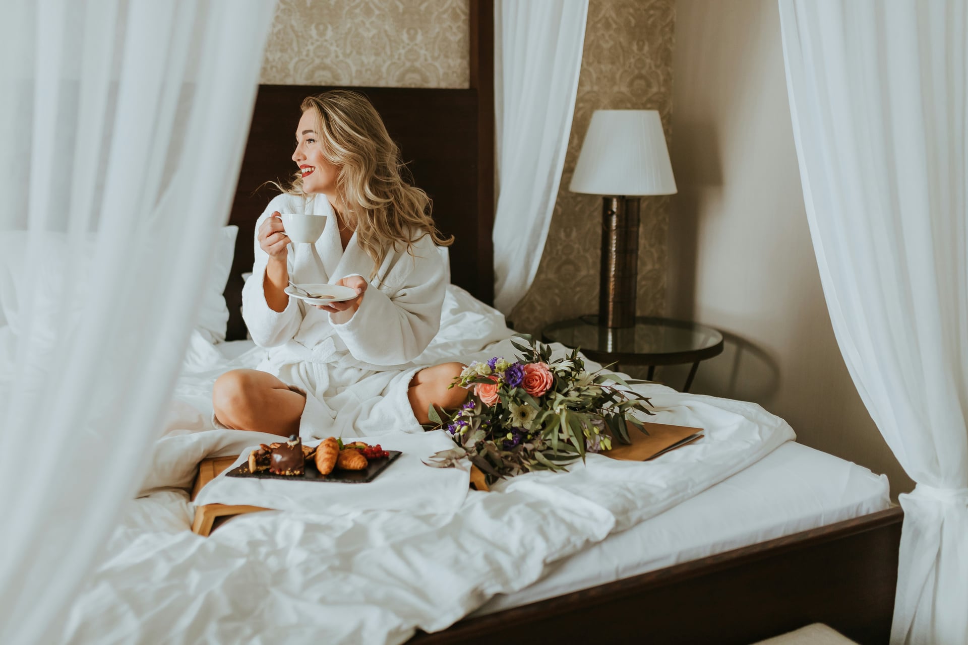 A guest enjoying coffee and breakfast in a canopy bed